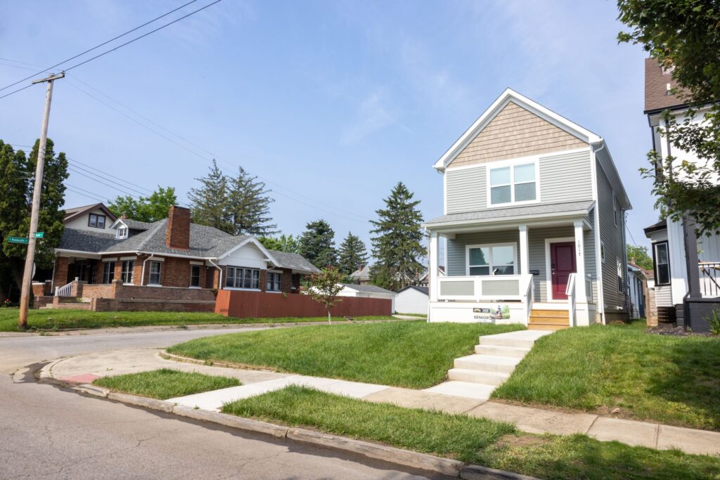 tan and gray house sitting on the corner of a street