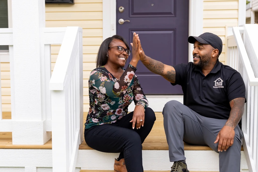 man and woman sitting on the front steps of a house, doing a high-five